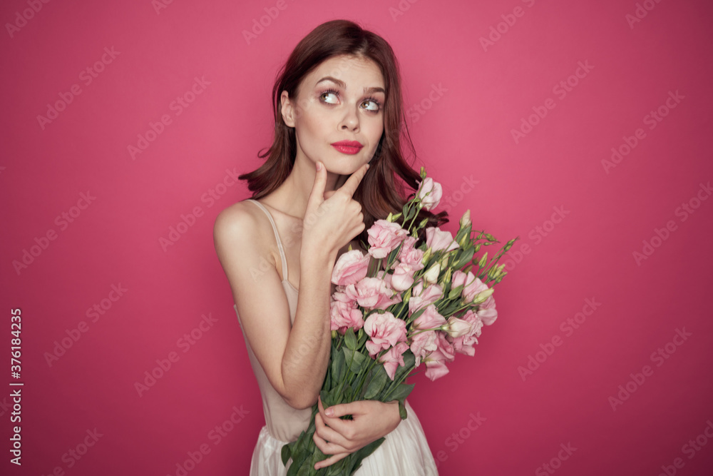 beautiful woman with a bouquet of flowers on a pink background in a light dress makeup model beautiful woman with a bouquet of flowers on a pink background in a light dress makeup model