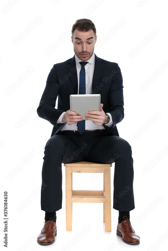 Interested businessman looking at tablet and smiling Interested businessman looking at tablet and smiling