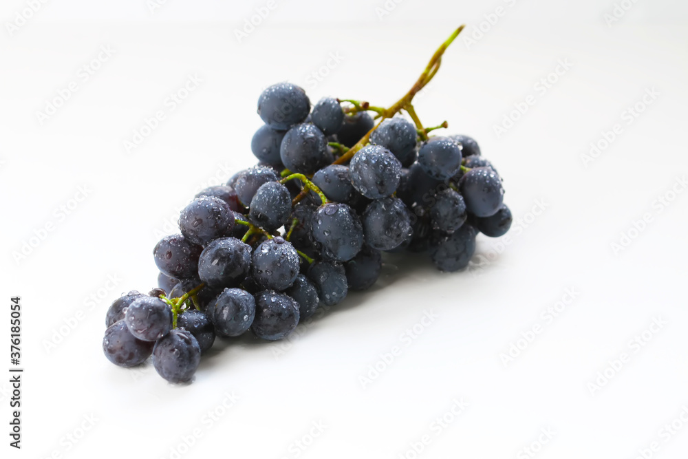 Black grapes, large fresh fruits with green leaves on a white background Black grapes, large fresh fruits with green leaves on a white background