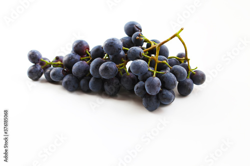 Black grapes, large fresh fruits with green leaves on a white background