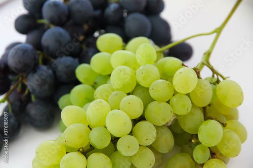 Green grapes . Large bunch of fresh fruit with green leaves and white backgrounds