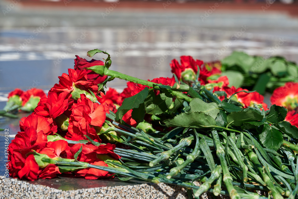 flowers on the memorial to fallen soldiers, red carnations on black marble, Russian text - monument to the unknown soldier