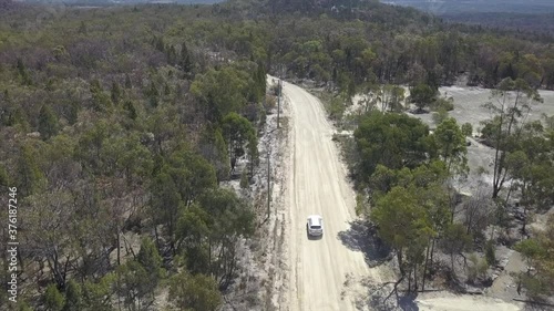 Aerial: Drone following a white vehicle as it drives along a sandy road in the Australian bush, near Stanthorpe Queensland  photo