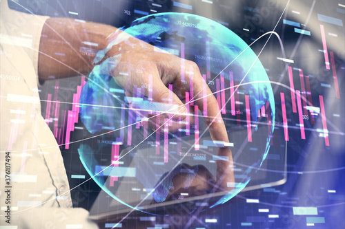 Double exposure of man's hands holding and using a digital device and forex graph drawing. Financial market concept.