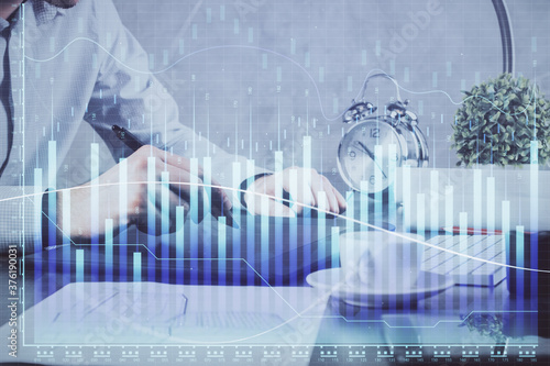 Double exposure of man's hands holding and using a phone and financial graph drawing. Analysis concept. © peshkova