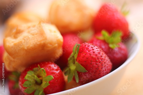 Fresh strawberries and profiteroles with ice cream in a white bowl