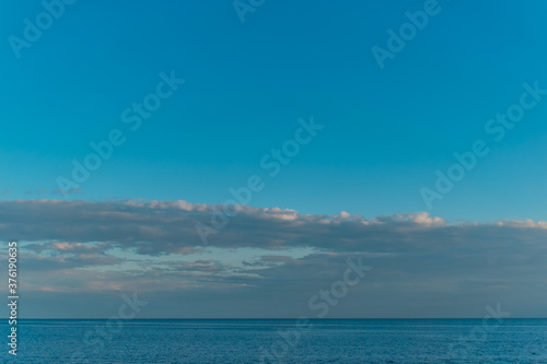 view of the clear calm undulating water of Lake Baikal  sunset clouds on the horizon  blue sky background