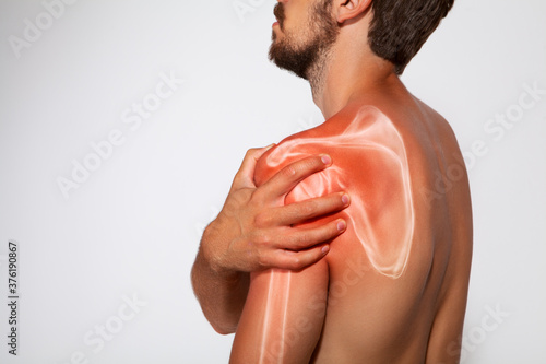 Shoulder scapula pain, man holding a hand on a painful zone