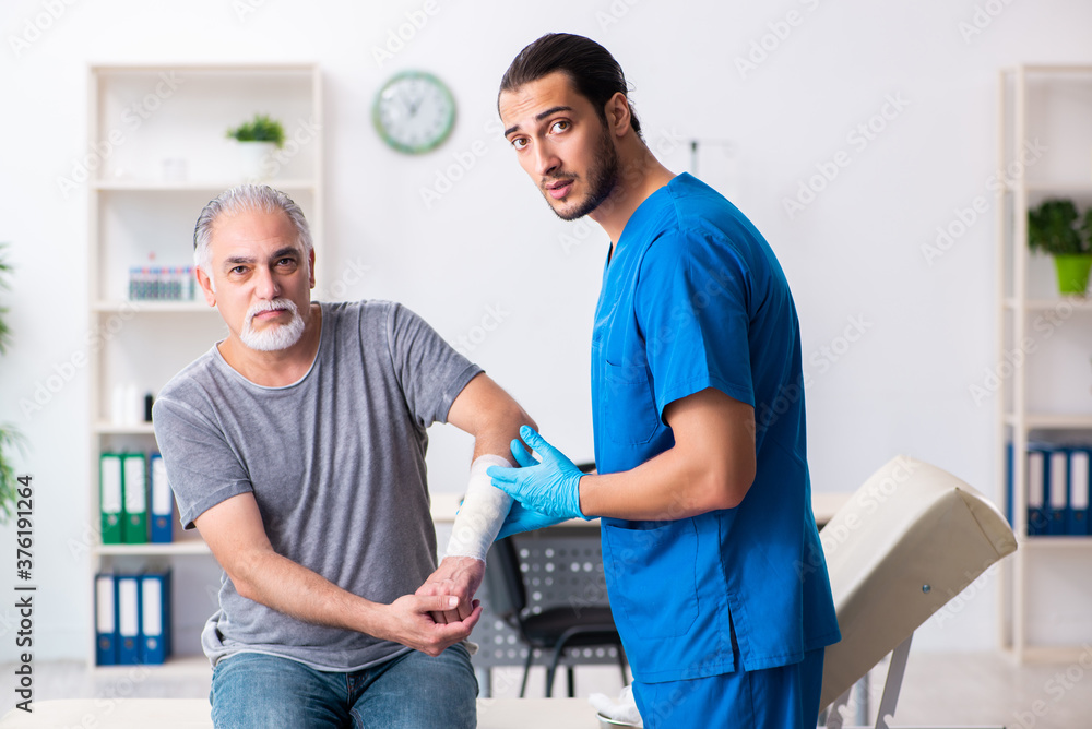 Obraz premium Young male doctor and old patient in first aid concept