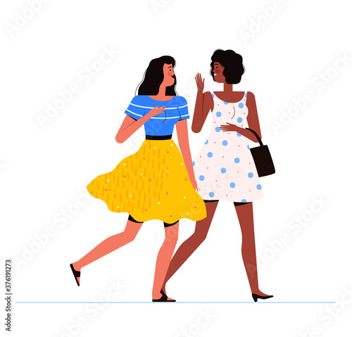 Two young women are walking together, laughing and talking. Communication, friendship and communication concept
