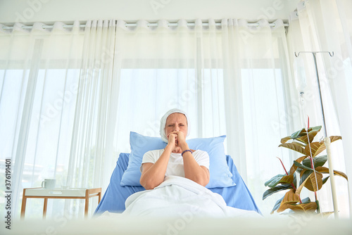 White caucasian female hairless and eyebrowless feel bad are praying and waiting for chemotherapy  in hospital room, breast cancer awareness month concept. photo