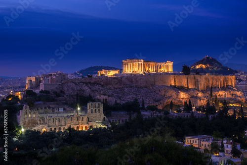 Iconic view of Acropolis hill in Athens, Greece at night. Delicate lights of Parthenon and Odeon theater. UNESCO world heritage.