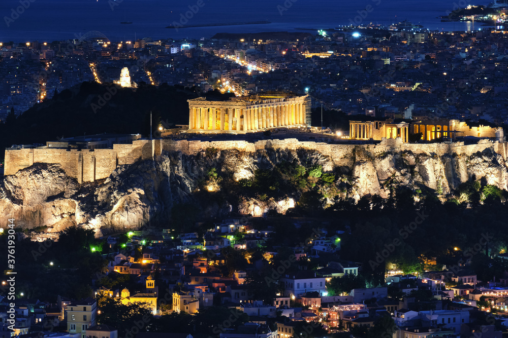Close view of Acropolis Parthenon and Erechtheion, Philoppapos monument at night. City lights of Athens. Famous iconic view of UNESCO world heritage.