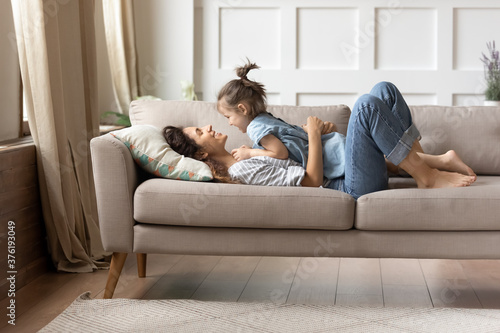 Obraz na plátně In cozy living room on comfy couch lying mother and her little cheery daughter