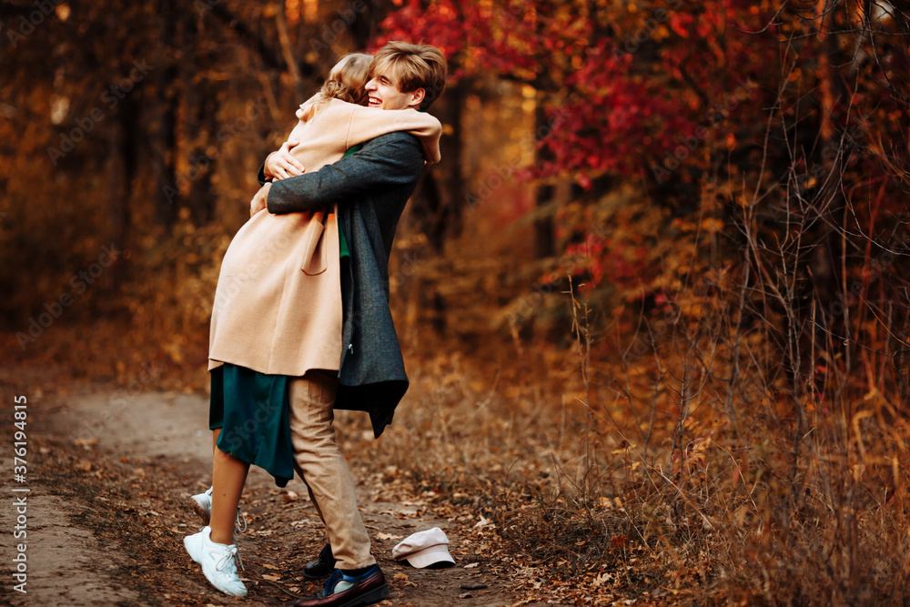 happy, couple in love hugs and smiles on the street, autumn, green scarf and cap, beige coat. man and woman on a date, valentines day. walk in the park under an umbrella in the rays of the setting sun happy, couple in love hugs and smiles on the street, autumn, green scarf and cap, beige coat. man and woman on a date, valentines day. walk in the park under an umbrella in the rays of the setting sun