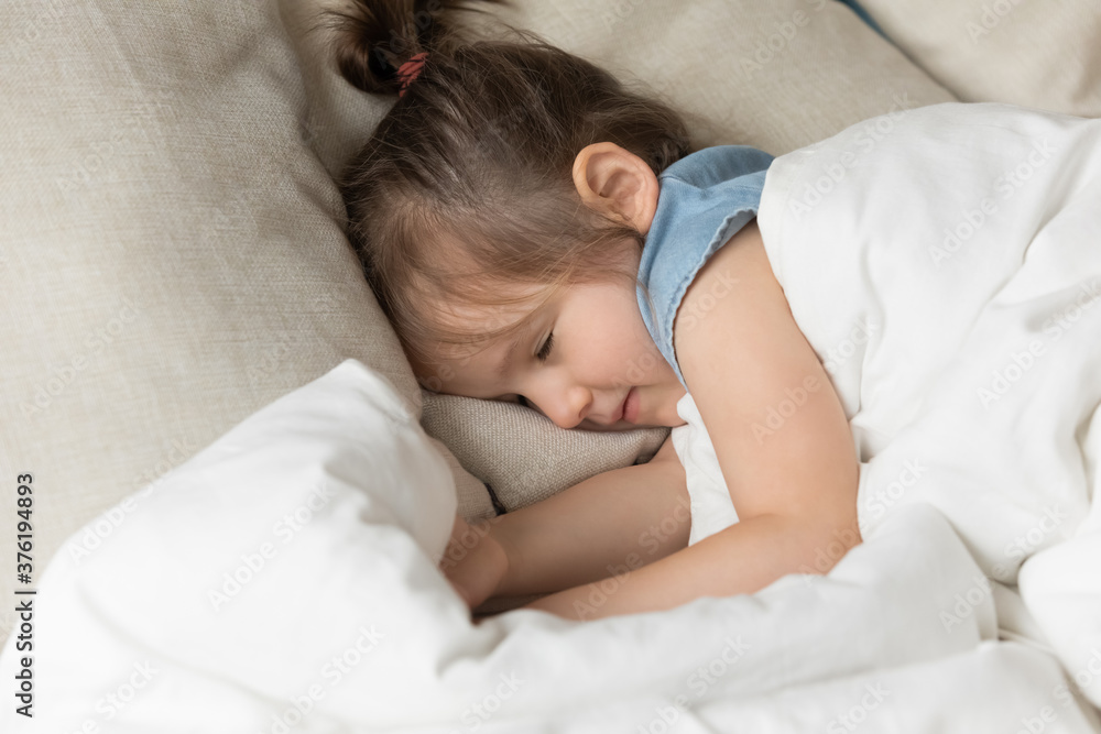 Close up little girl sleeping in bed under warm hypoallergenic duvet orthopedic mattress soft pillow. Healthy daytime nap or night rest for health and growth of children, high quality bedding concept Close up little girl sleeping in bed under warm hypoallergenic duvet orthopedic mattress soft pillow. Healthy daytime nap or night rest for health and growth of children, high quality bedding concept