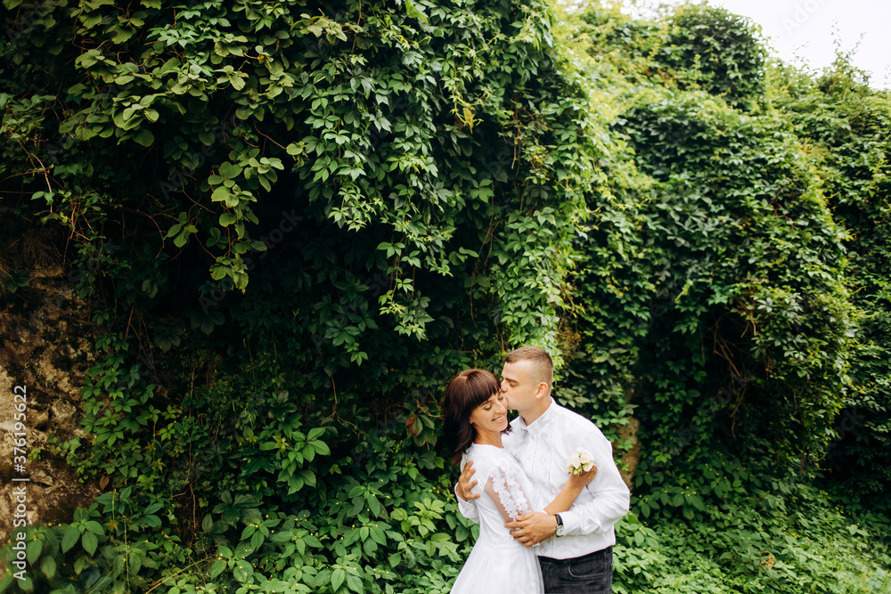 Lovely couple standing on a background of green leaves Lovely couple standing on a background of green leaves