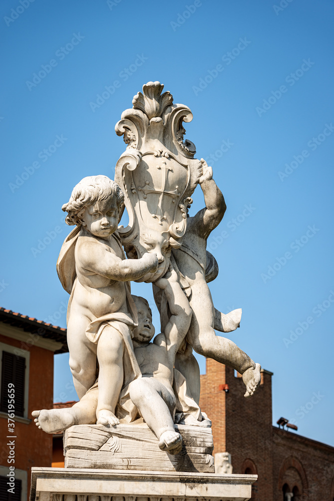 Putti fountain (Fontana dei Putti), Square of Miracles (Piazza dei Miracoli), Pisa, Tuscany, Italy. Three marble cherubs support the coat of arms of the city. Sculptor, Giovanni Antonio Cybei