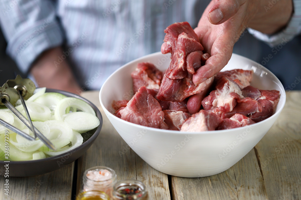 Soft focus. The chef prepares meat for barbecue. Pieces of meat in a bowl. Raw onion rings. Soft focus. The chef prepares meat for barbecue. Pieces of meat in a bowl. Raw onion rings.