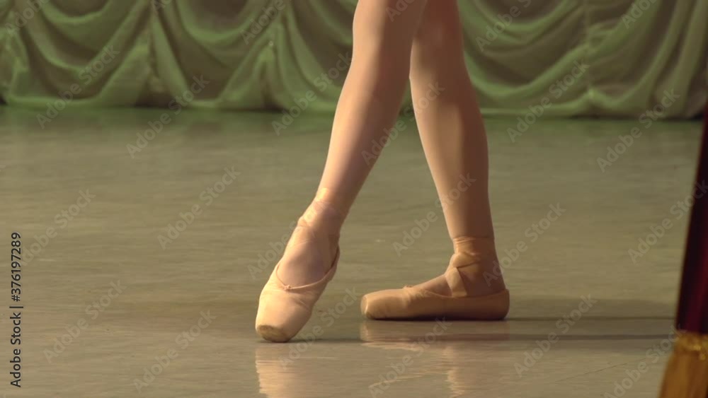 Legs of a Ballerina in a Bow. Ballerina's feet in pointe shoes move slowly in dance on stage. Slow Motion at a rate of 120 fps Legs of a Ballerina in a Bow. Ballerina's feet in pointe shoes move slowly in dance on stage. Slow Motion at a rate of 120 fps
