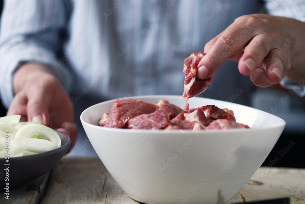 Soft focus. The chef prepares meat for barbecue. Pieces of meat in a bowl. Raw onion rings. Soft focus. The chef prepares meat for barbecue. Pieces of meat in a bowl. Raw onion rings.