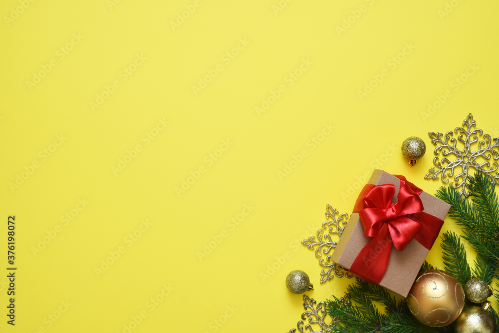 Christmas yellow background with fir, christmas balls and decor. Top view with space for copy.