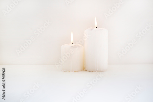 two white candles with fire on white background
