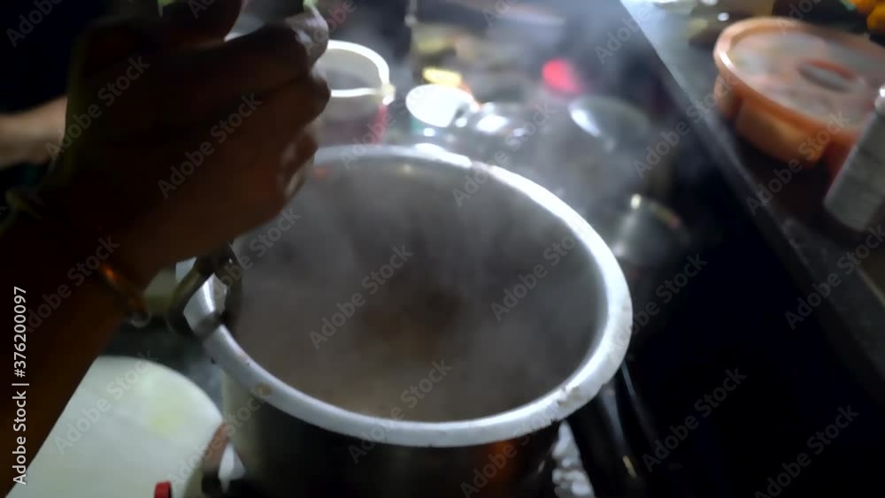 Holding The Boiling Tea Mixture For Tandoori Chai On A Pot Using Tongs And Pours It Into Plastic Jug. - Close Up