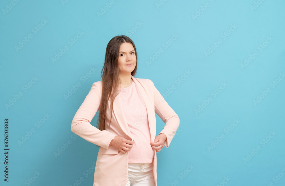 funny young pregnant woman in pink t-shirt on blue background, woman cannot wear clothes, small clothes funny young pregnant woman in pink t-shirt on blue background, woman cannot wear clothes, small clothes