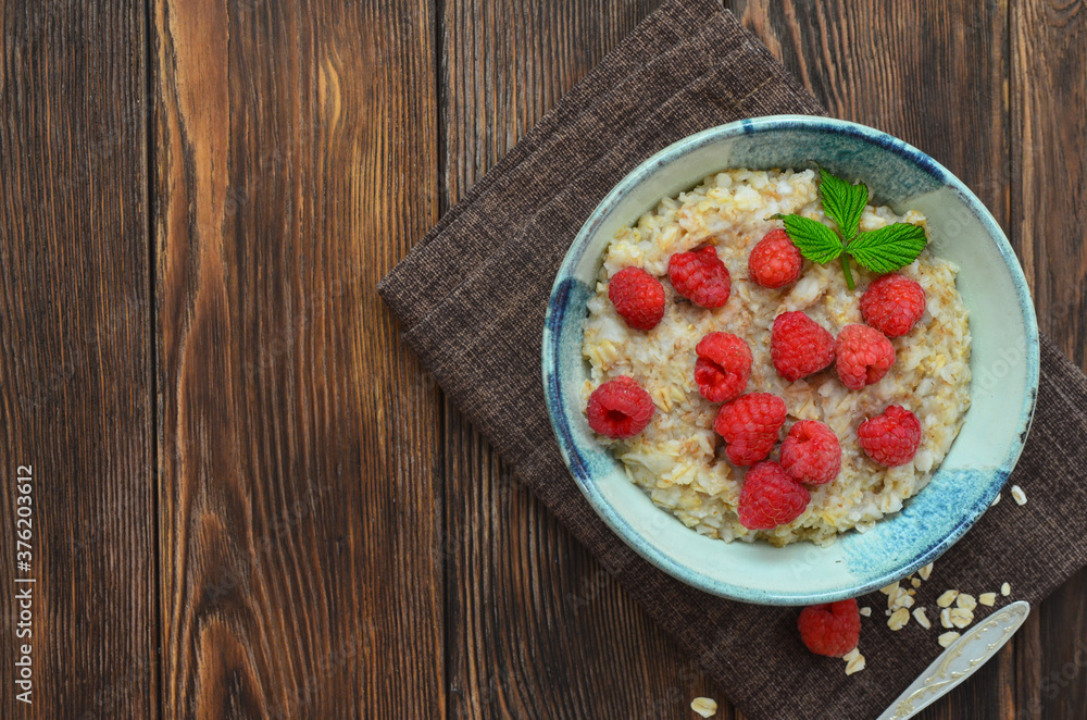 Delicious and hearty breakfast oatmeal porridge with raspberries in a beautiful ceramic bowl. The concept of healthy food, diet, organic nutrition and lifestyle. Space for text and design Delicious and hearty breakfast oatmeal porridge with raspberries in a beautiful ceramic bowl. The concept of healthy food, diet, organic nutrition and lifestyle. Space for text and design
