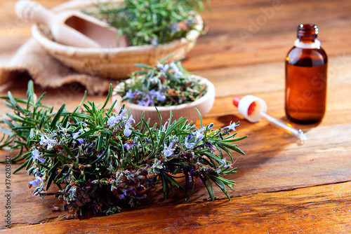 wooden table with green rosemary and an essential oil preparation