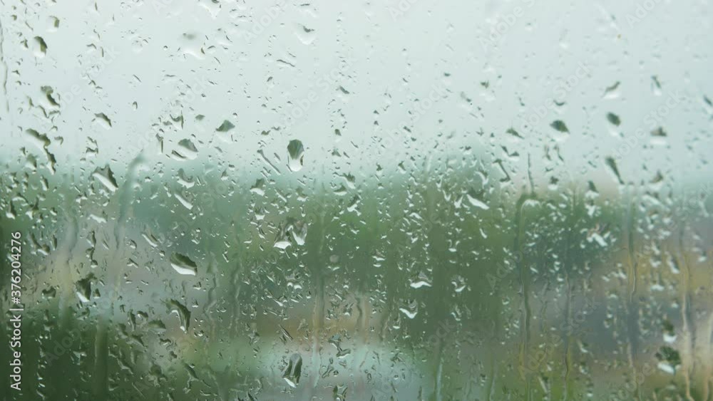 Rain drops sliding slow on window glass in rainy day, medium closeup shot Rain drops sliding slow on window glass in rainy day, medium closeup shot