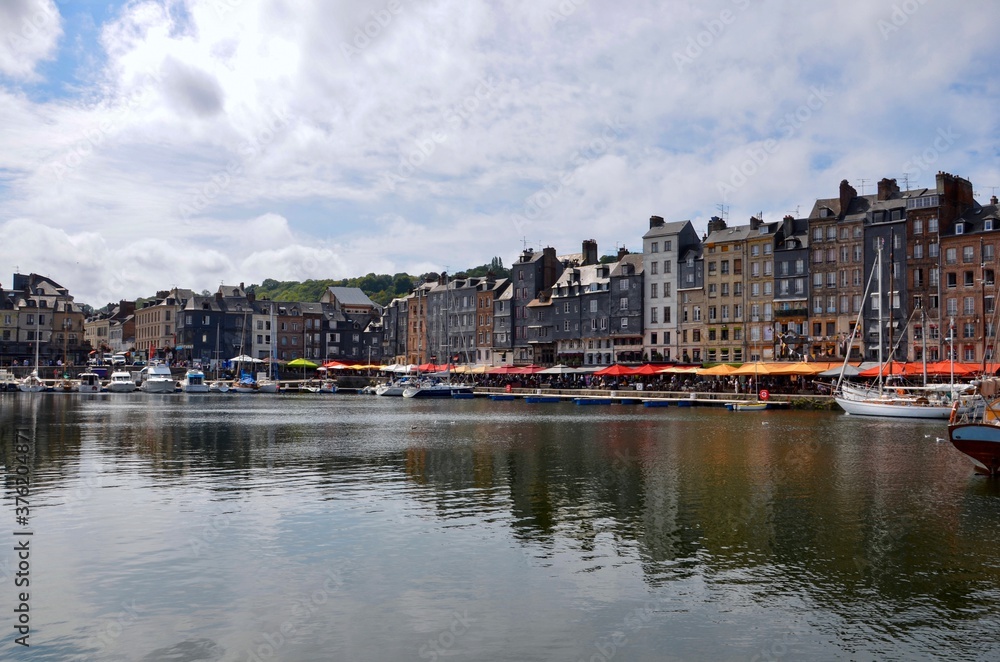 Old port (Vieux Bassin) of the town Honfleur in the county of Calvados in Normandy, France, colorfol parasols in front, a sunny day in summer, blue sky background