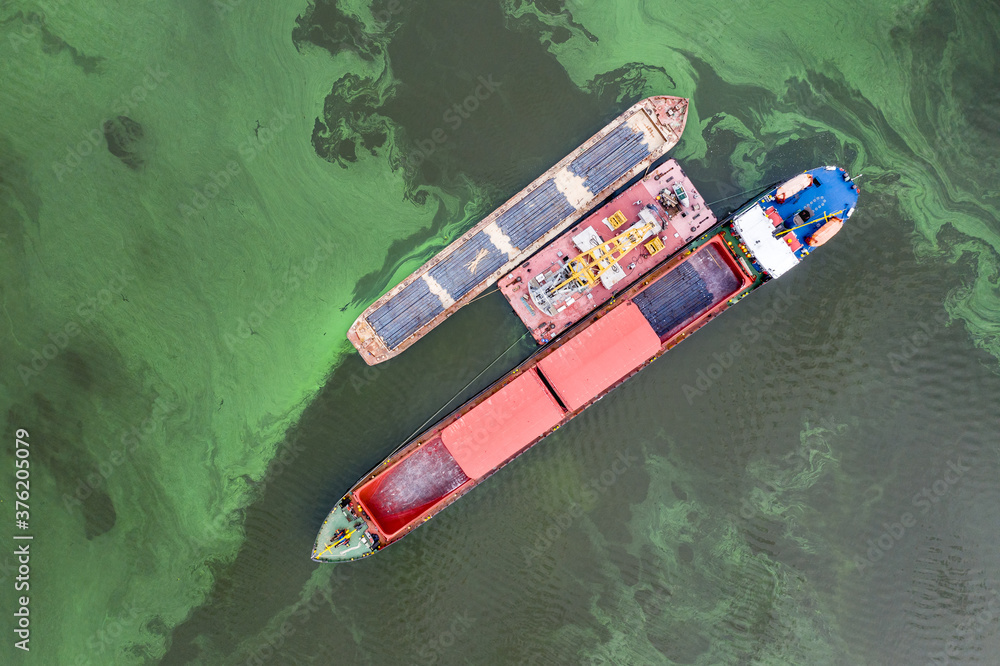 A cargo ship is loading cargo onto a barge. River crane. Water area of the Dnieper River, Ukraine. View from top.