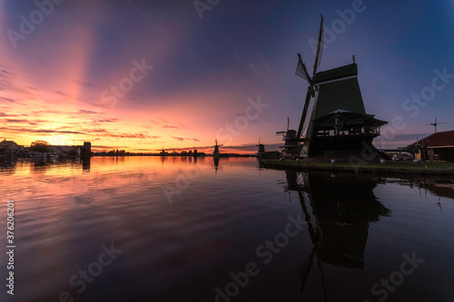 Vivid sunset light beams casts behind the Zaanse Schans city and windmill at the late evening, Netherlands