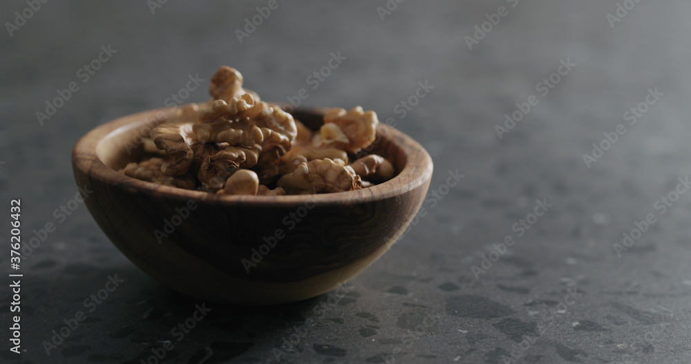 walnut kernels in wooden bowl on terrazzo countertop walnut kernels in wooden bowl on terrazzo countertop