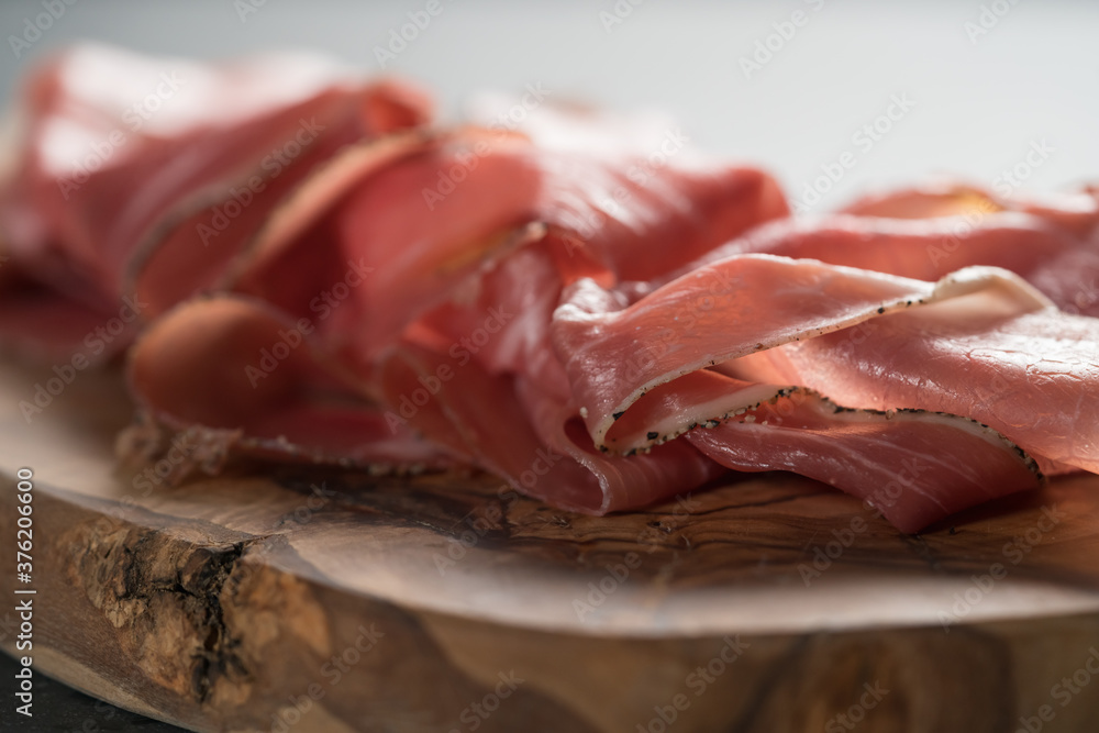 Sliced prosciutto ham on olive wood board Sliced prosciutto ham on olive wood board