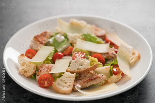 Fresh caesar salad with chicken and cherry tomatoes in white bowl