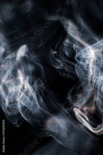 White smoke from incense stick isolated against dark background