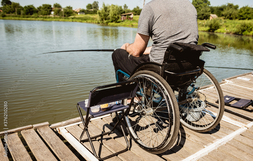Obraz premium Young disabled man in a wheelchair fishing.