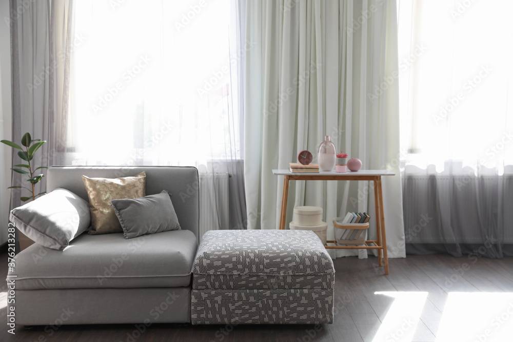 Fototapeta premium Elegant living room with comfortable sofa near windows. Interior design