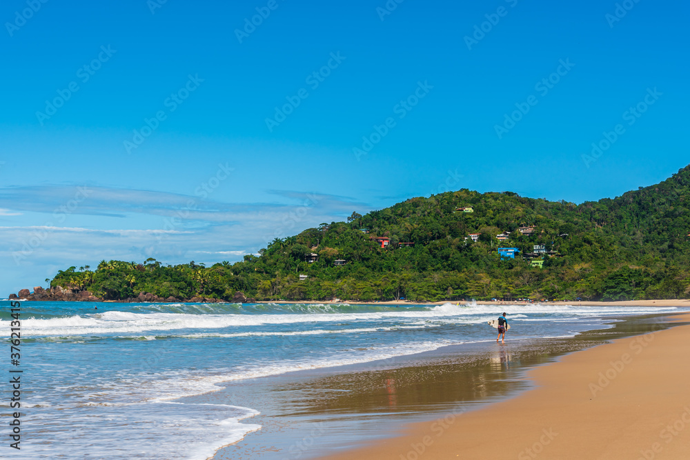Surfer walking along beautiful beach shore in Brazil Surfer walking along beautiful beach shore in Brazil