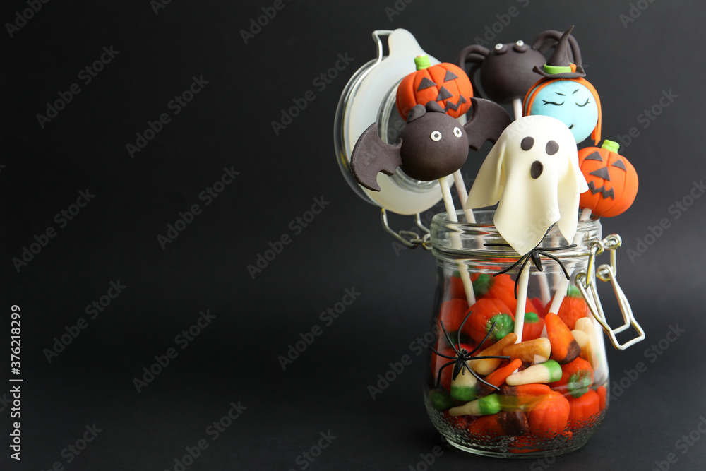 Delicious Halloween themed cake pops on black background, space for text