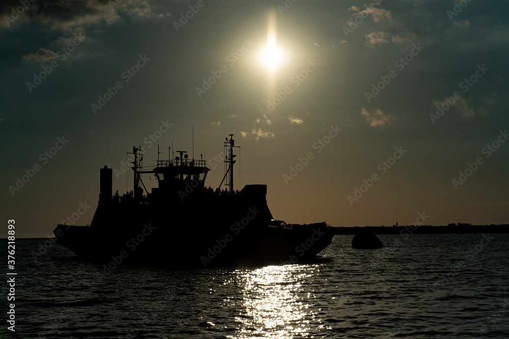 Fototapeta premium Transportation ferry at sea in the rays of the evening sun.