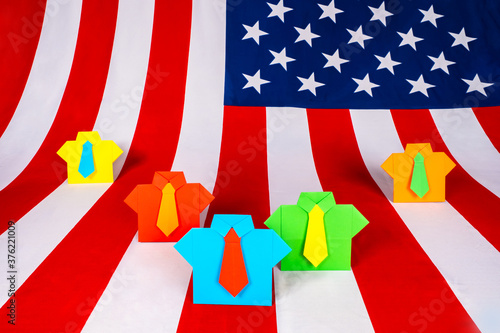 Fototapeta Naklejka Na Ścianę i Meble -  Colorful origami business suits on the background of the American flag. Election race in the United States. American politicians on the background of the flag of the United States of America.