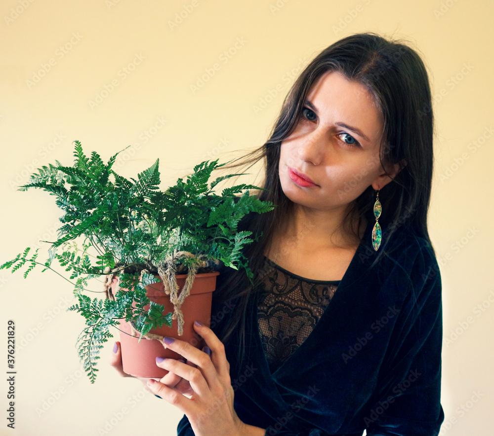 Beautiful young woman in a boho style outfit with an unusual specimen of domestic fern with furry rhizomes: Davallia tyermanii Beautiful young woman in a boho style outfit with an unusual specimen of domestic fern with furry rhizomes: Davallia tyermanii