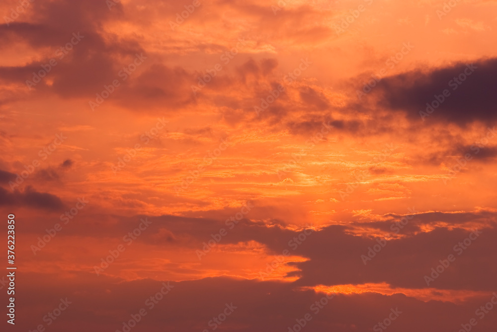 Fire sky background. Soft clouds with the hint of the sun at sunset. Many orange tones and patterns of clouds.