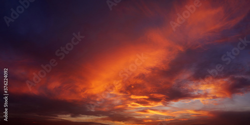 Dark blood red sky background. Dramatic heavy clouds with the hint of the sun at sunset. Many orange tones and patterns of clouds. © Digihelion