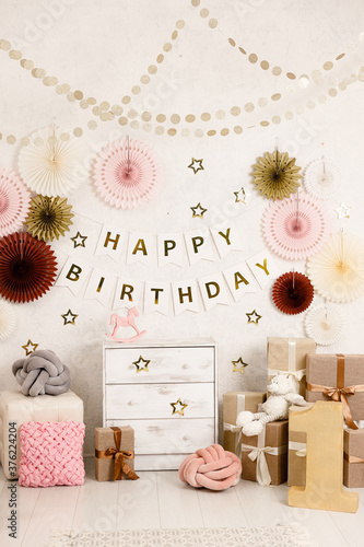 Birthday decorations - gifts, toys, balloons, garland and figure for little baby party on a white wall background. photo