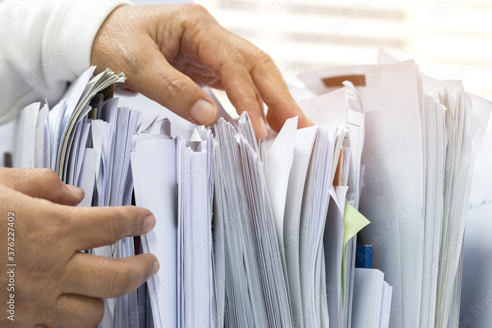 Office workers arranging stacks of lot documents report papers waiting be managed on desk in busy office. Concept of workload in business finacial paperwork information planing - obrazy, fototapety, plakaty 